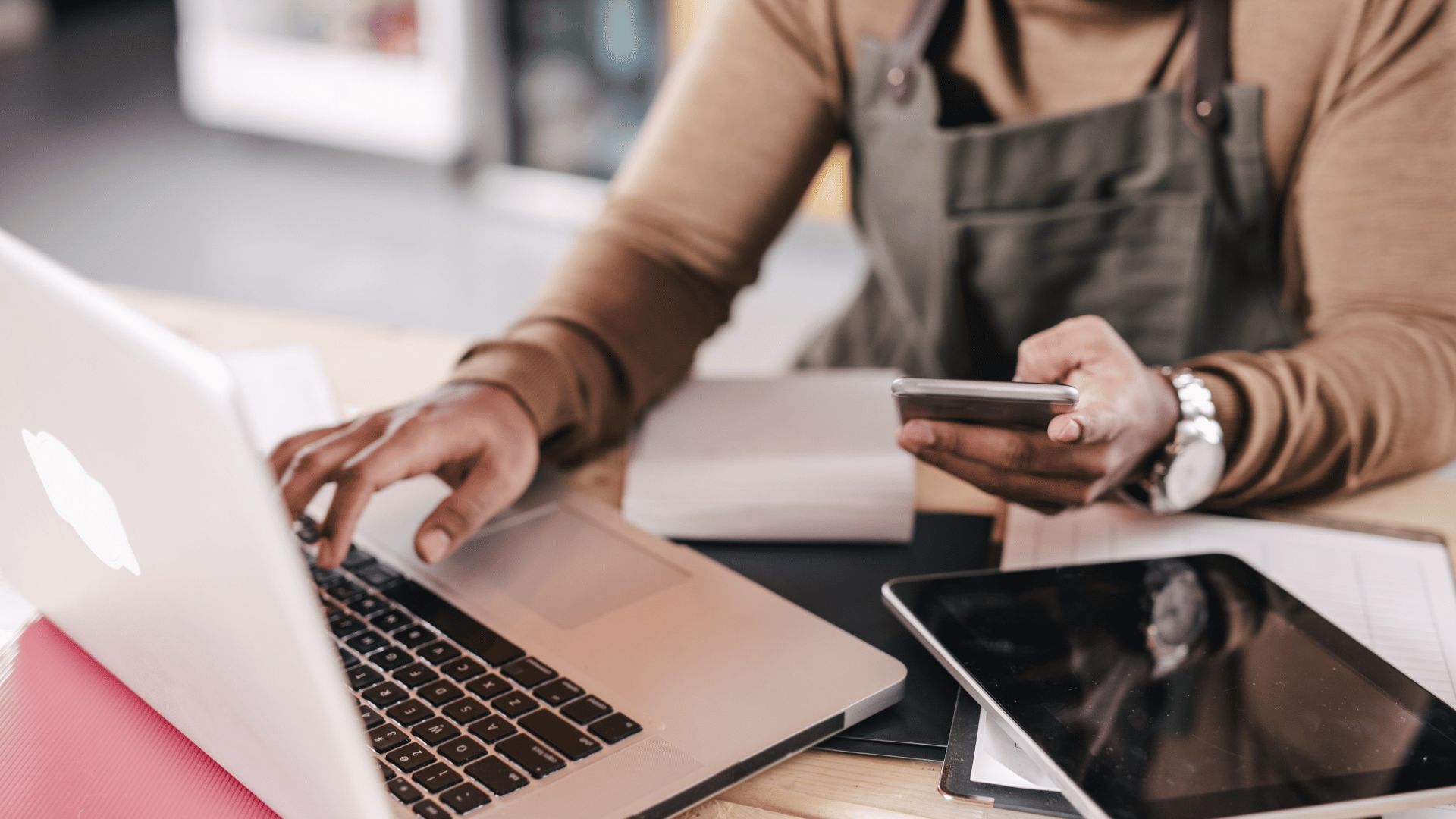 A café owner reconciling their accounts using a laptop and calculator